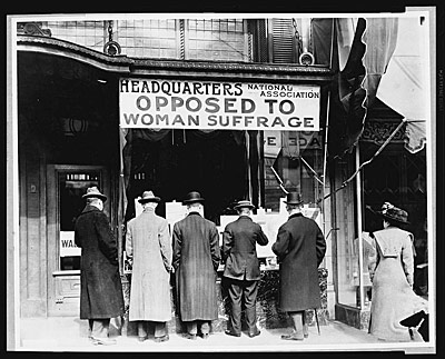 Picture of men standing in front of a sign that says National Association Headquarters Opposed to Woman Suffrage